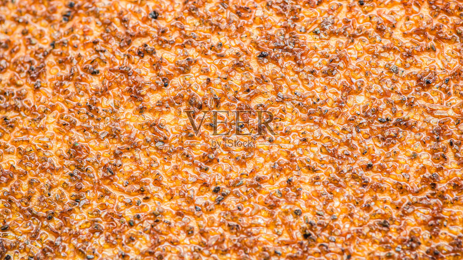 橙色砂纸颗粒的特写，展示了其磨砂质感。照片摄影图片