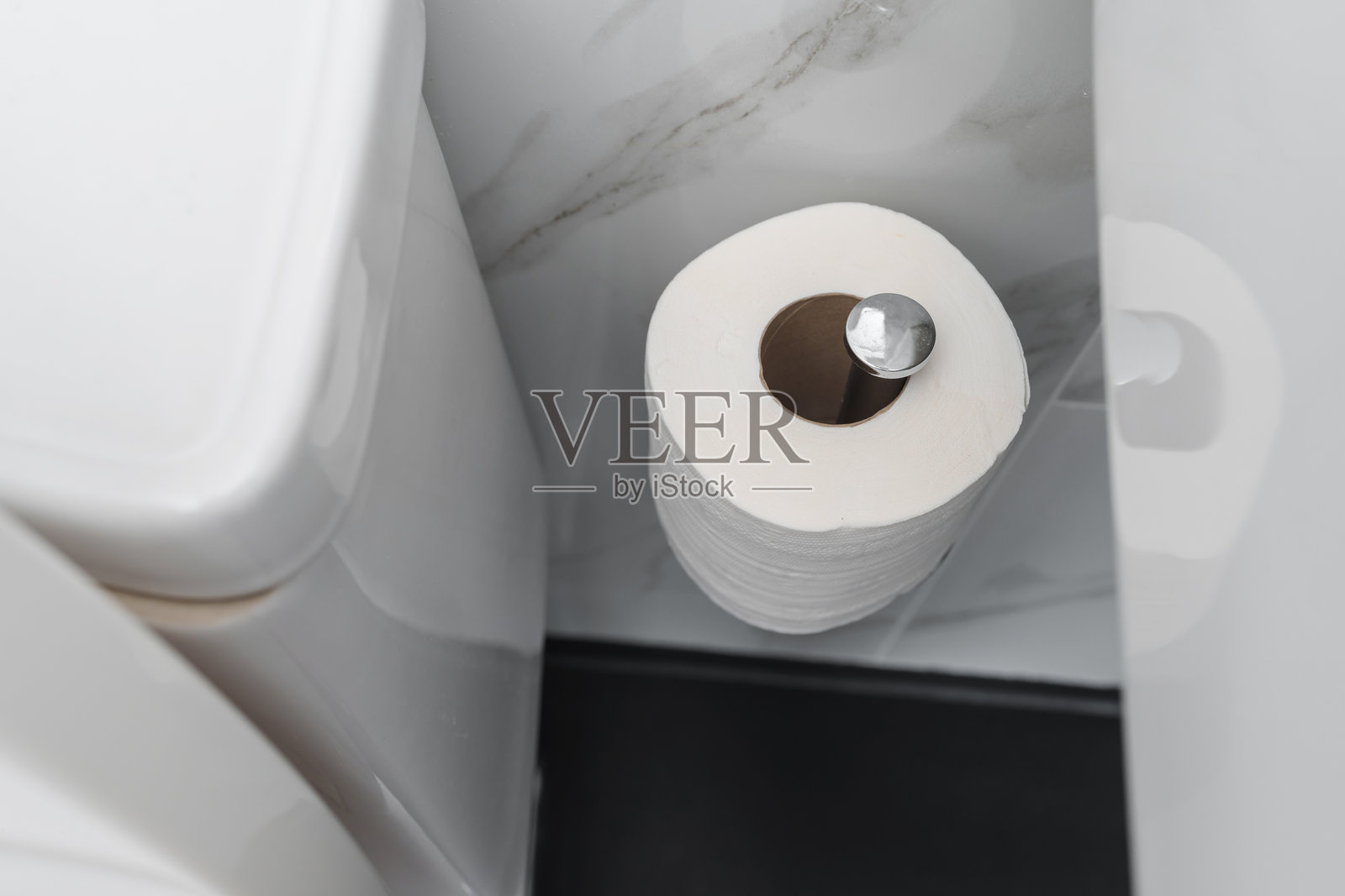 浴室里墙上挂着的卫生纸卷，旁边有一个马桶。照片摄影图片