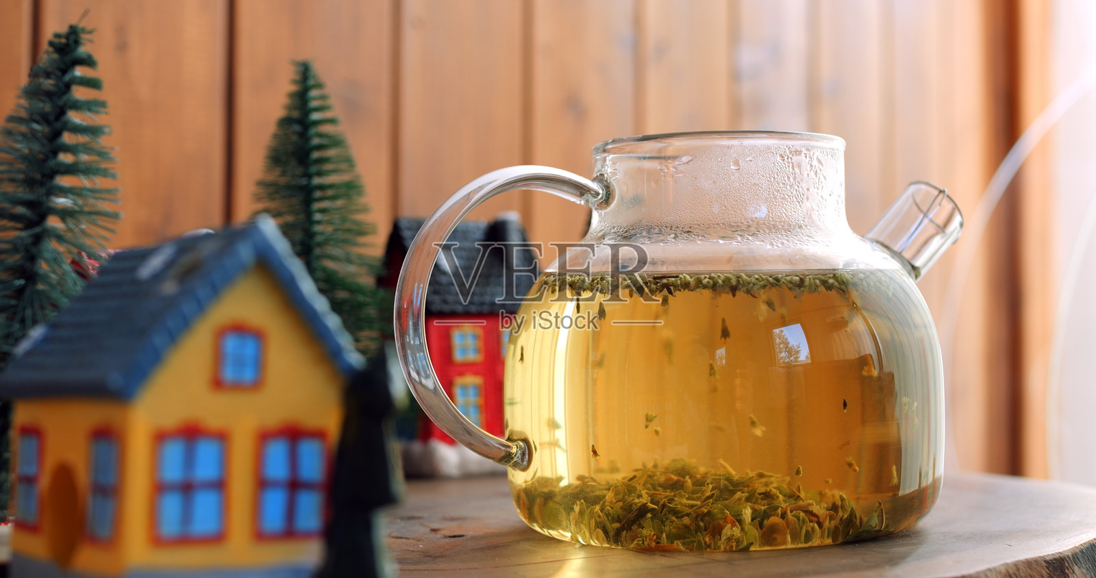 温暖的草本茶在玻璃茶壶中冲泡，为冬季环境增添了一丝温馨。周围是乡村风格的装饰，茶的轻柔蒸汽和天然成分邀请人们放松和享受舒适。照片摄影图片
