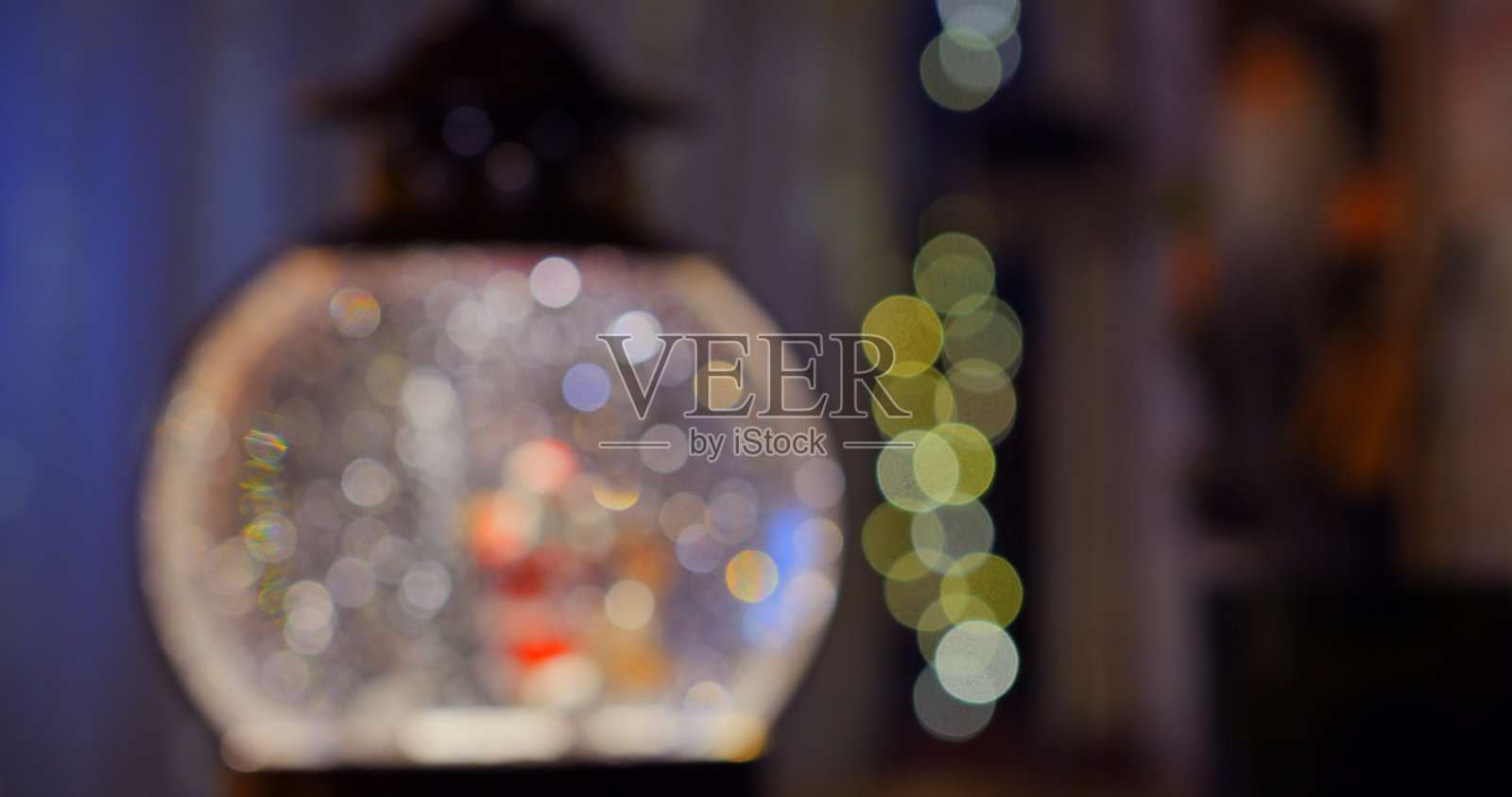 模糊的圣诞老人和驯鹿在雪花球中重现经典冬季童话。闪烁的雪花和节日装饰为周围环境增添了一丝魔幻的节日奇迹。灯光和雪花的模糊效果。照片摄影图片