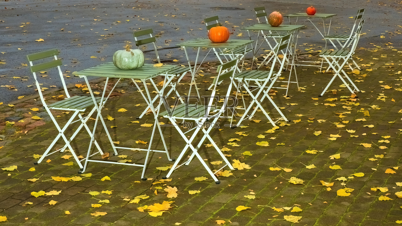 温暖的秋夜，户外咖啡馆的桌椅。照片摄影图片