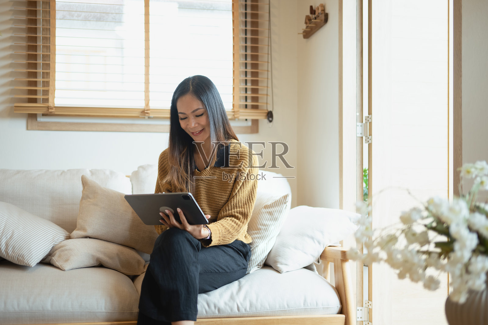 微笑的年轻女性在客厅使用平板电脑照片摄影图片