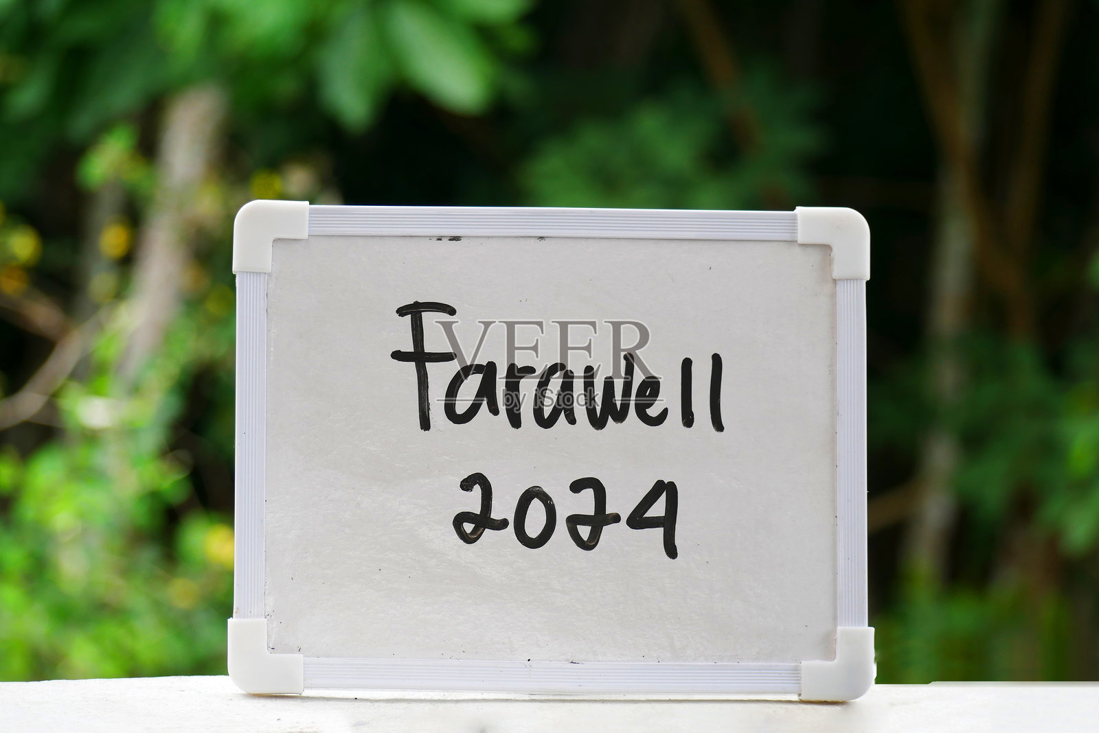 白色黑板上手写的“告别2024”，背景是模糊的森林。照片摄影图片