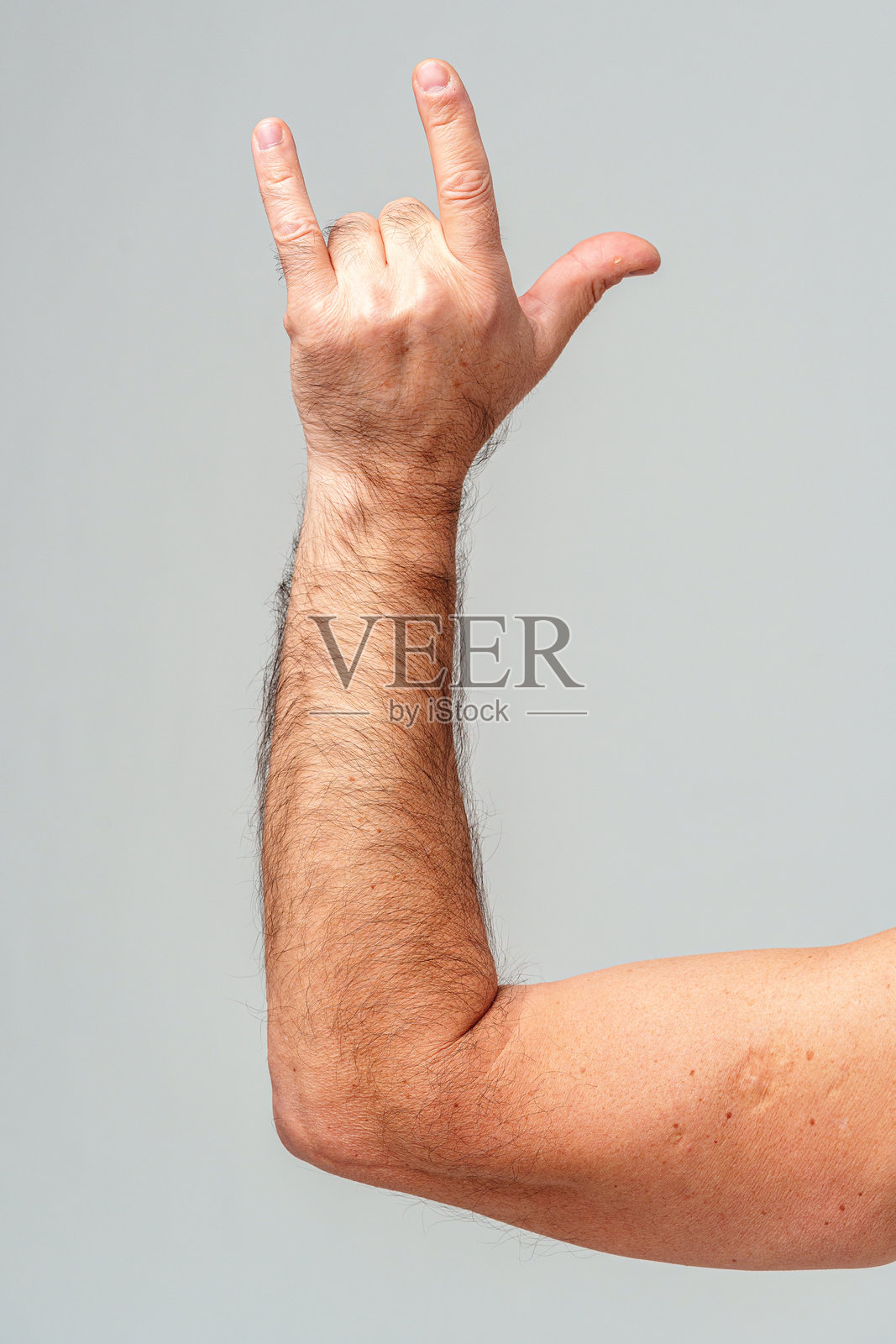 一个人用小指和食指竖起手势，背景简单。照片摄影图片