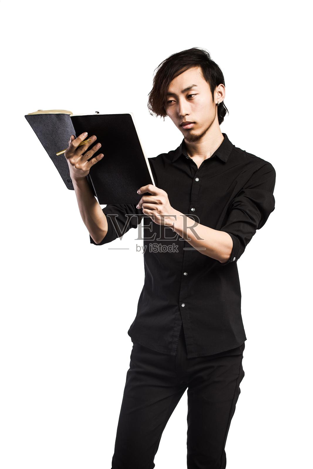 亚洲男子在笔记本上写字照片摄影图片