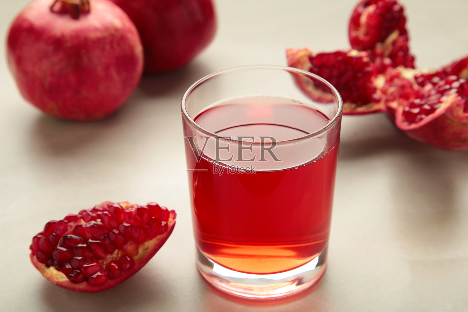 新鲜的石榴汁盛在玻璃杯中，旁边有石榴，背景为浅色。俯视图。照片摄影图片