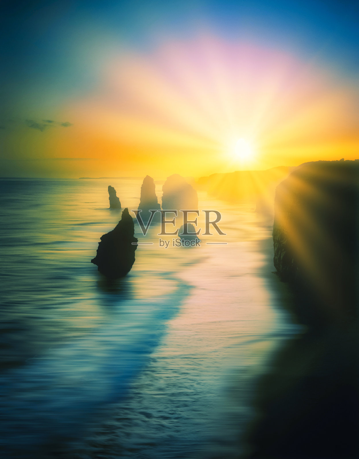 十二使徒背后的日出光芒，澳大利亚维多利亚州大洋路照片摄影图片