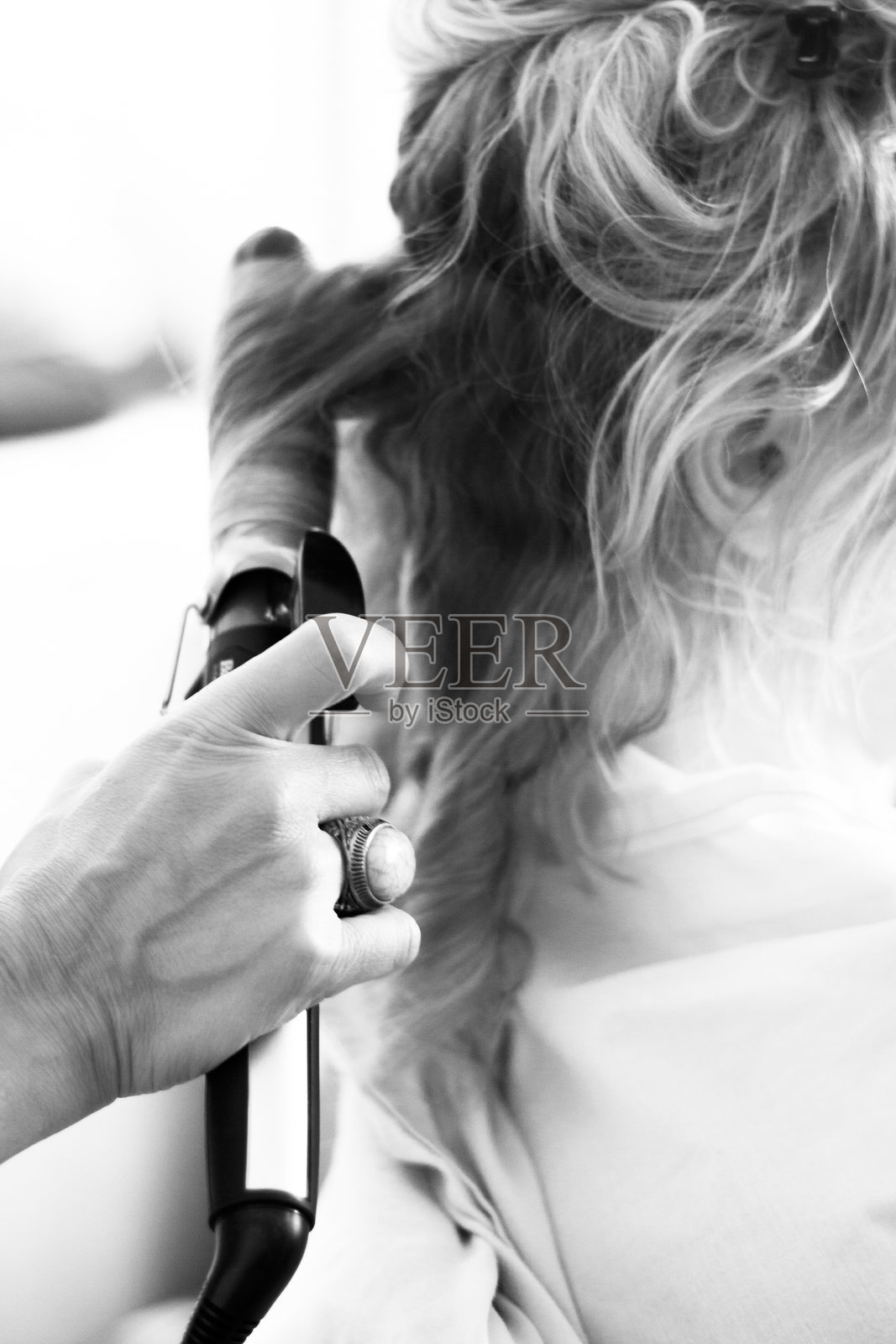 在明亮的下午，在沙龙用卷发棒为卷发造型照片摄影图片