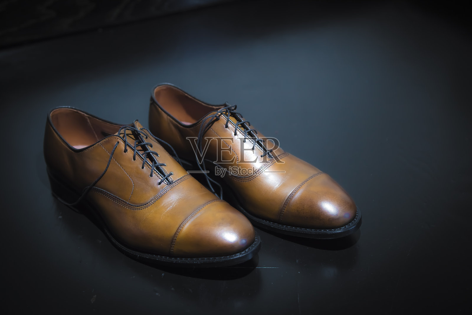 优雅的棕色皮革正装鞋在深色背景上，突显工艺与风格。照片摄影图片