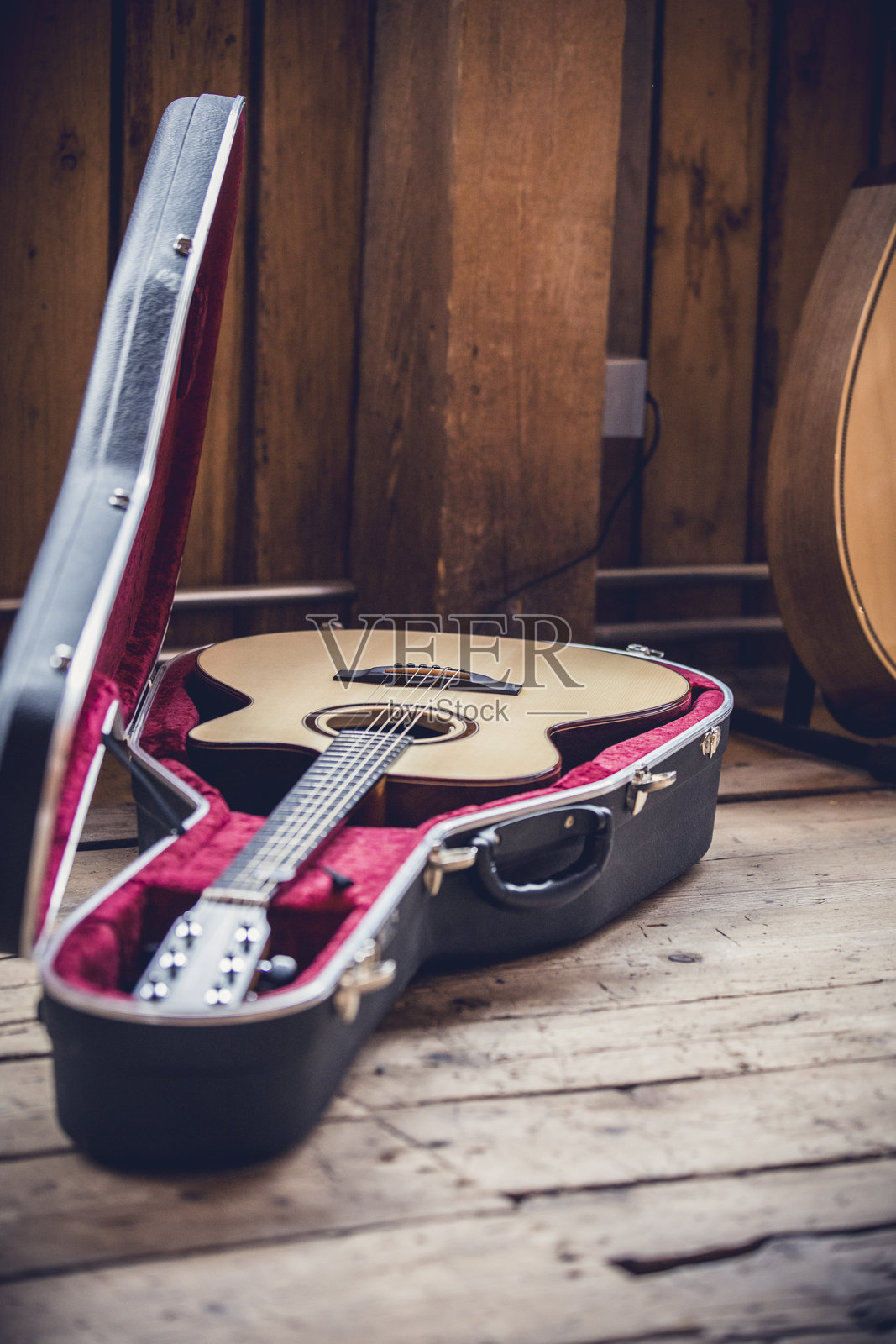 一把原声吉他静静地放在一个打开的复古吉他箱里，置于温馨房间的木地板上。照片摄影图片