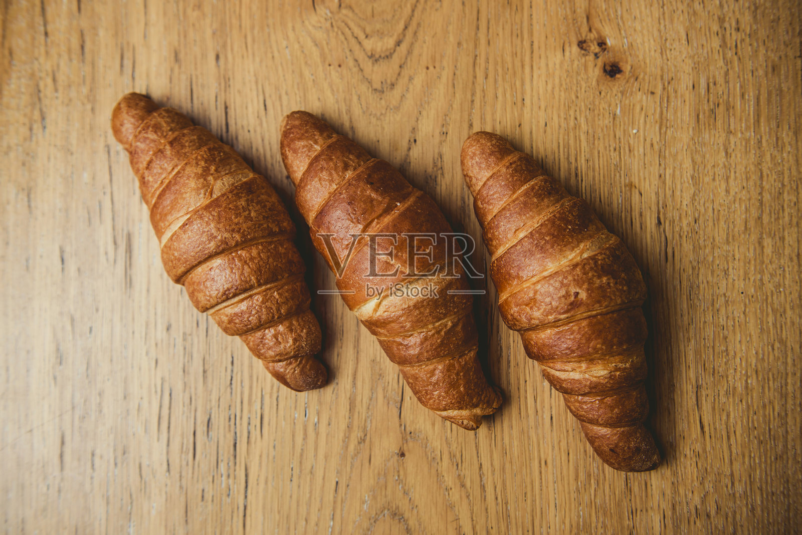 新鲜出炉的金色可颂面包放在乡村风格的木桌上照片摄影图片