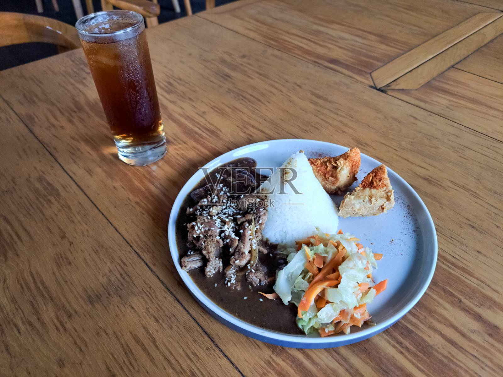 美味的牛肉 Bulgogi 配蒸米饭、炸豆腐或 Tahu Goreng、腌制蔬菜或 Acar Sayur 以及辛辣调味料。新鲜的冰茶装在玻璃杯中。食品和饮料菜单。照片摄影图片