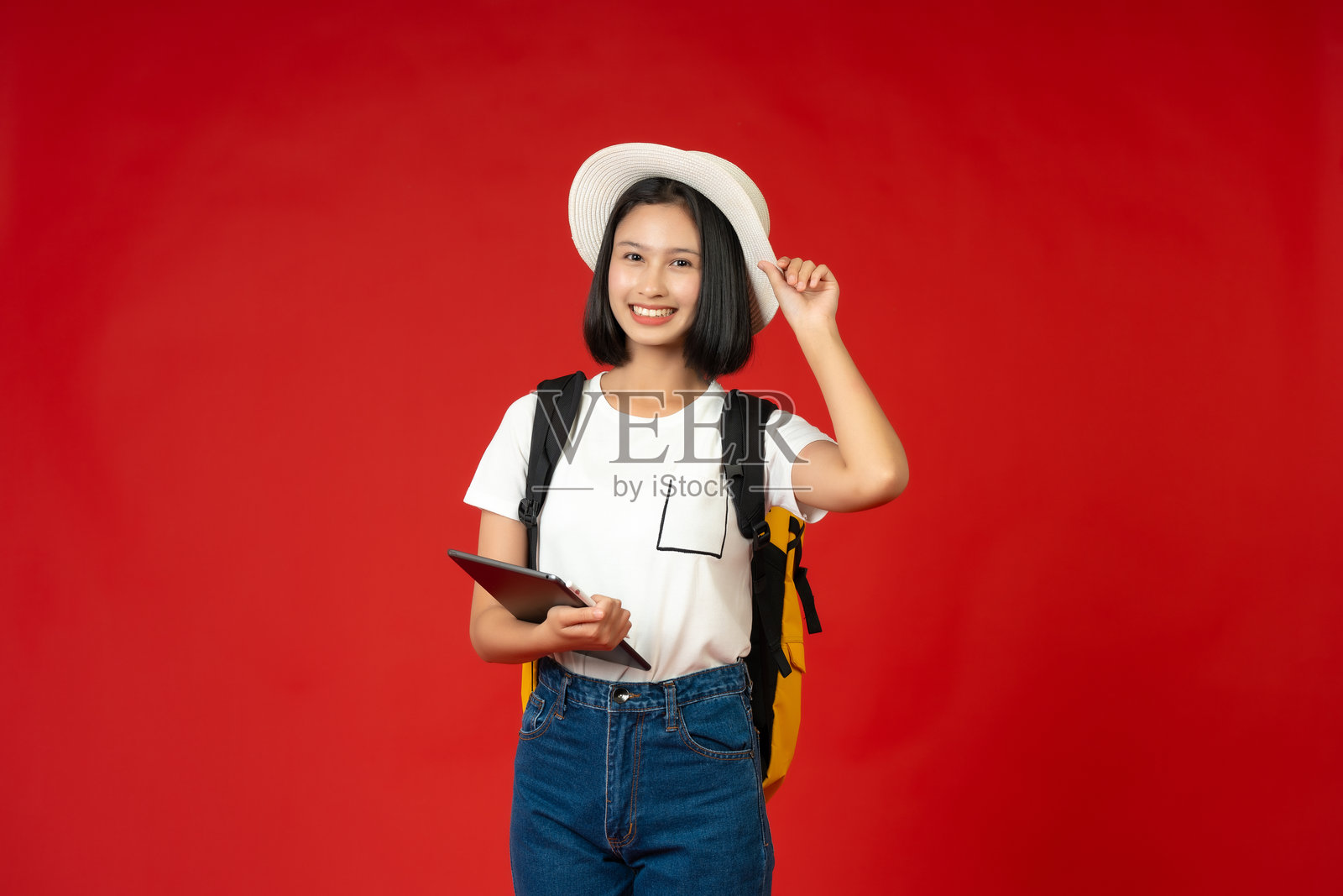 在精心布置的摄影棚中，一位亚洲少女正在平板电脑上阅读教科书，展现了她对教育和追求知识以实现美好未来的 dedication。照片摄影图片