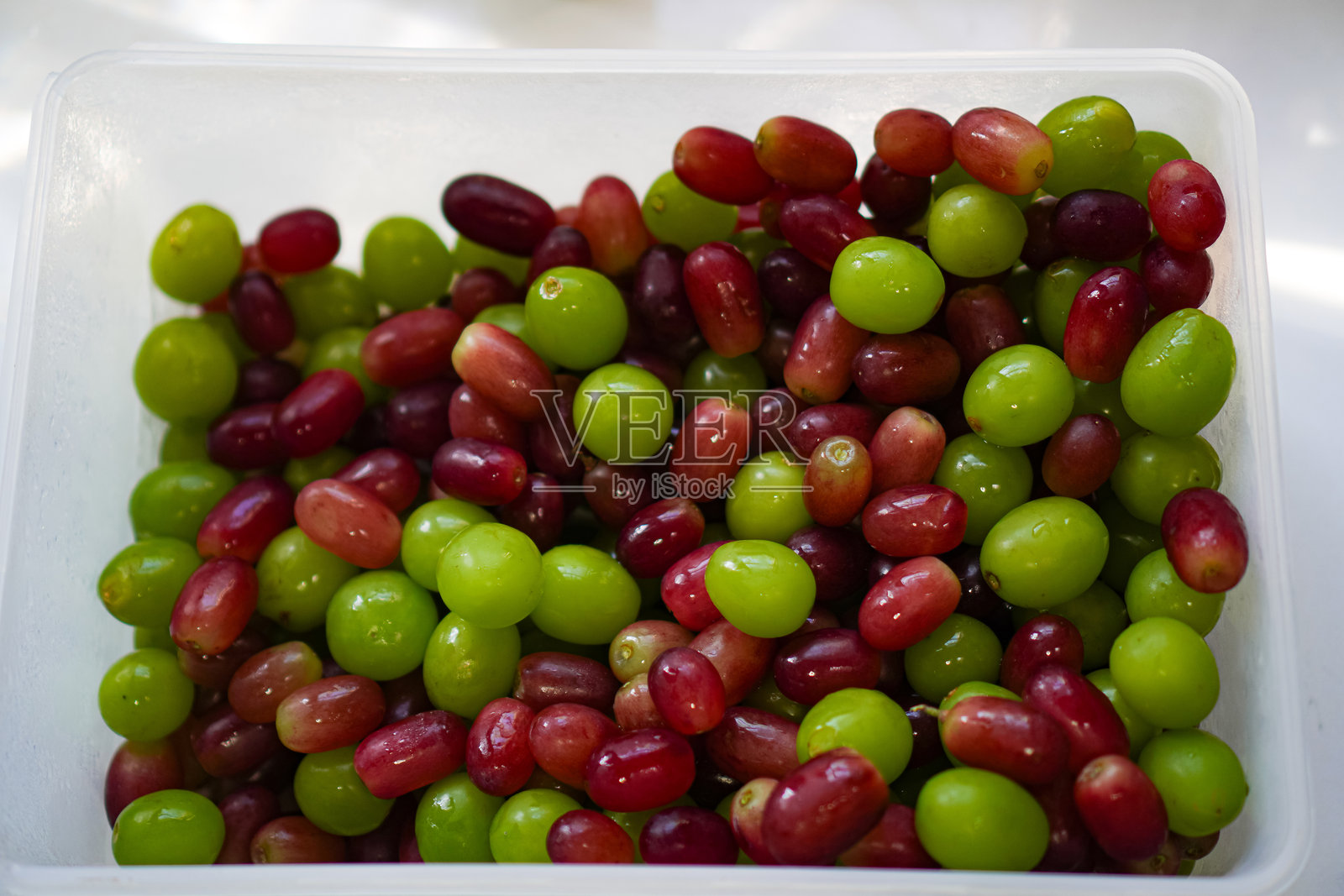 绿葡萄和红葡萄装在食品盒里作为晚餐零食吃的图片。照片摄影图片