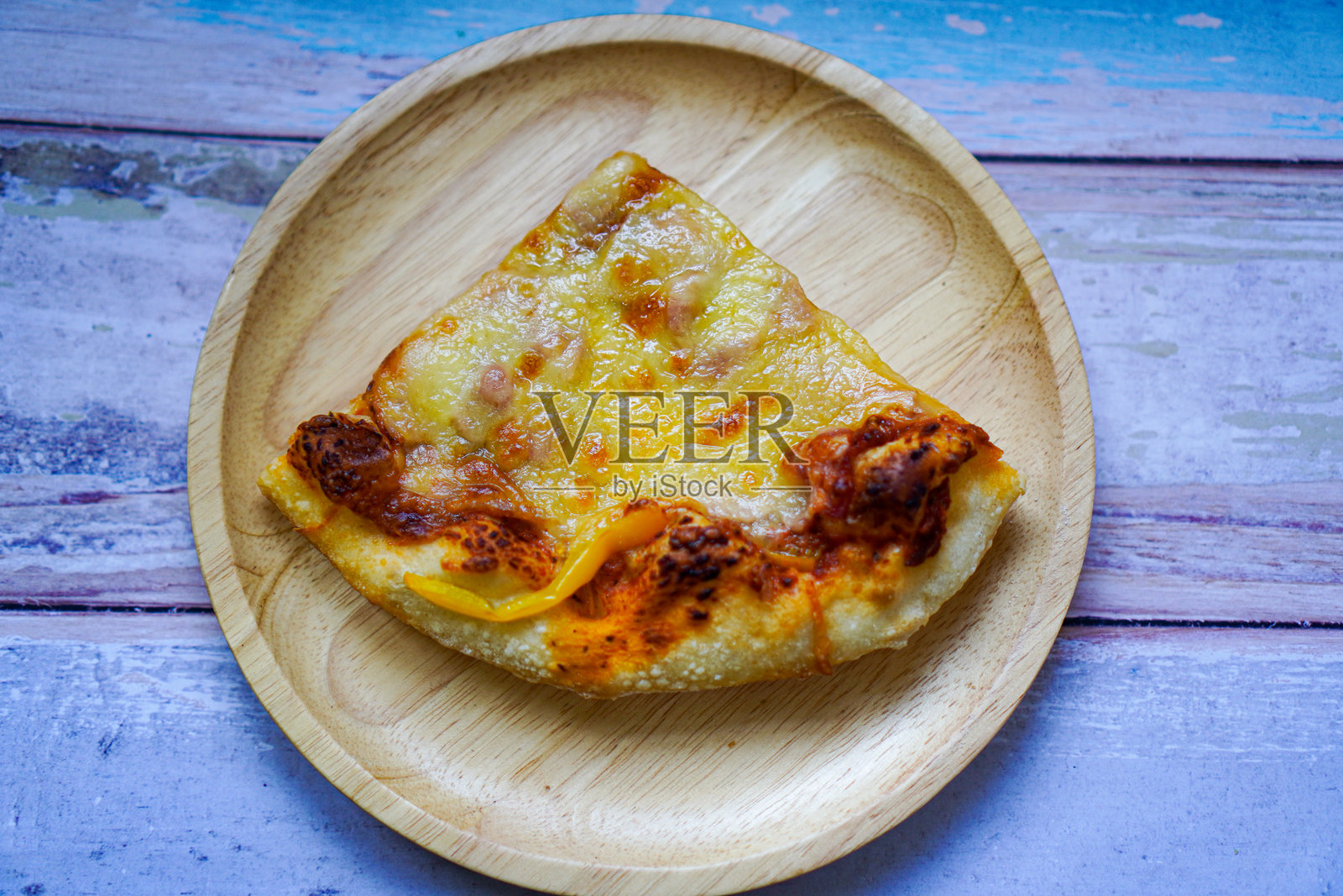 上图是自制的脆皮火腿芝士披萨放在餐盘上。照片摄影图片