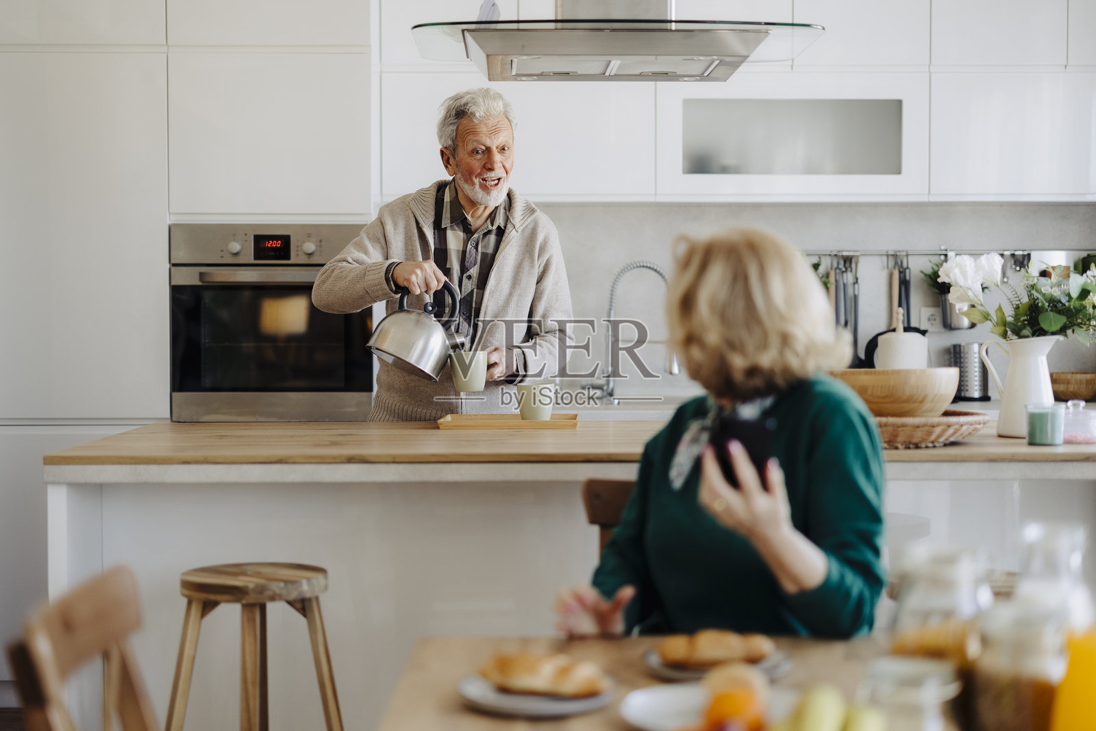 一对快乐的老年夫妇在家中交谈并享用早餐照片摄影图片