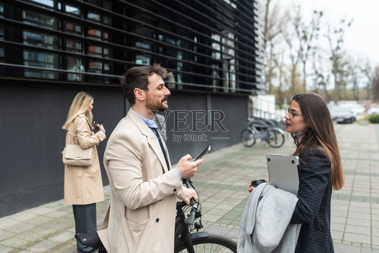一群商务人士在办公大楼前。女商人和男商人在户外交谈和讨论，交流想法，互致问候，谈论工作系统的创新。照片摄影图片