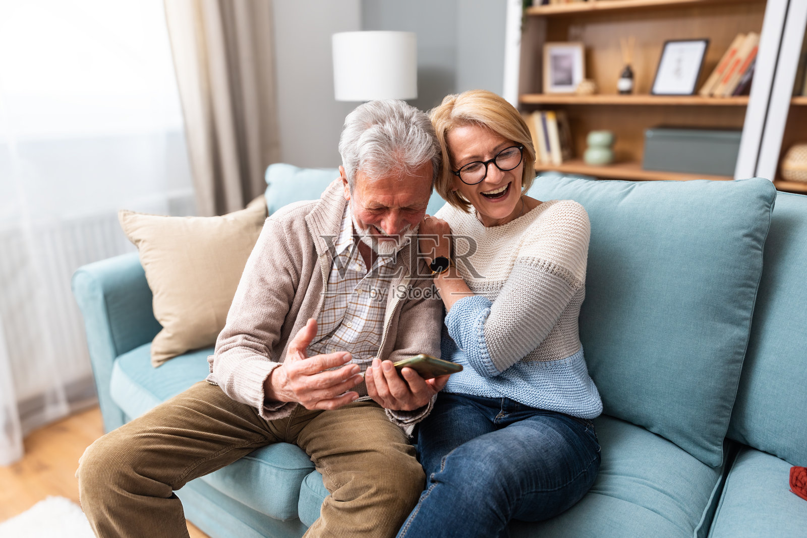 简单生活。退休的老年夫妇，男士和女士，坐在家中的沙发上，享受他们的生活和退休时光。相爱的人互相尊重，分享时刻，增进感情。照片摄影图片