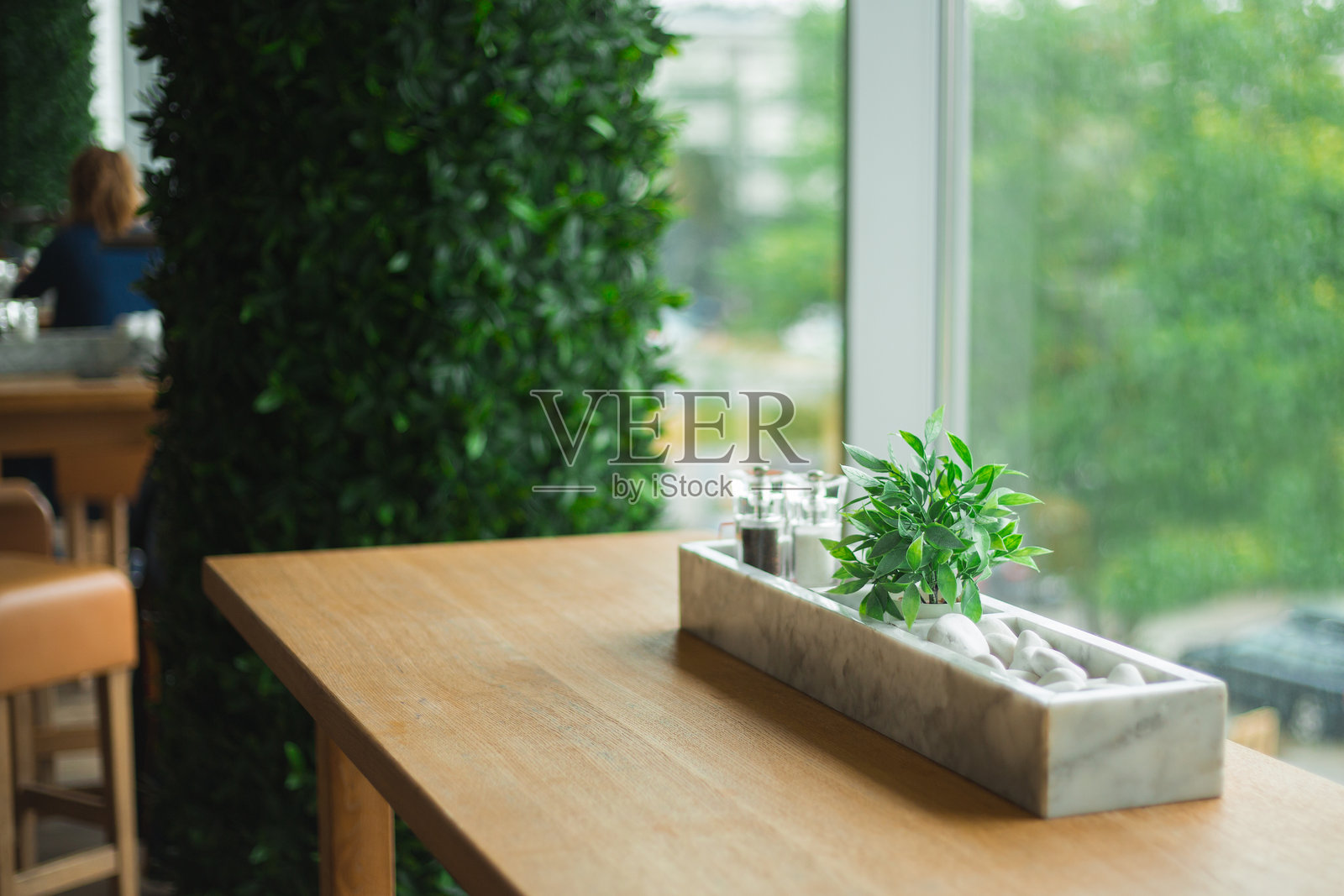 现代咖啡店室内，配有大窗户、松木桌和郁郁葱葱的植物照片摄影图片