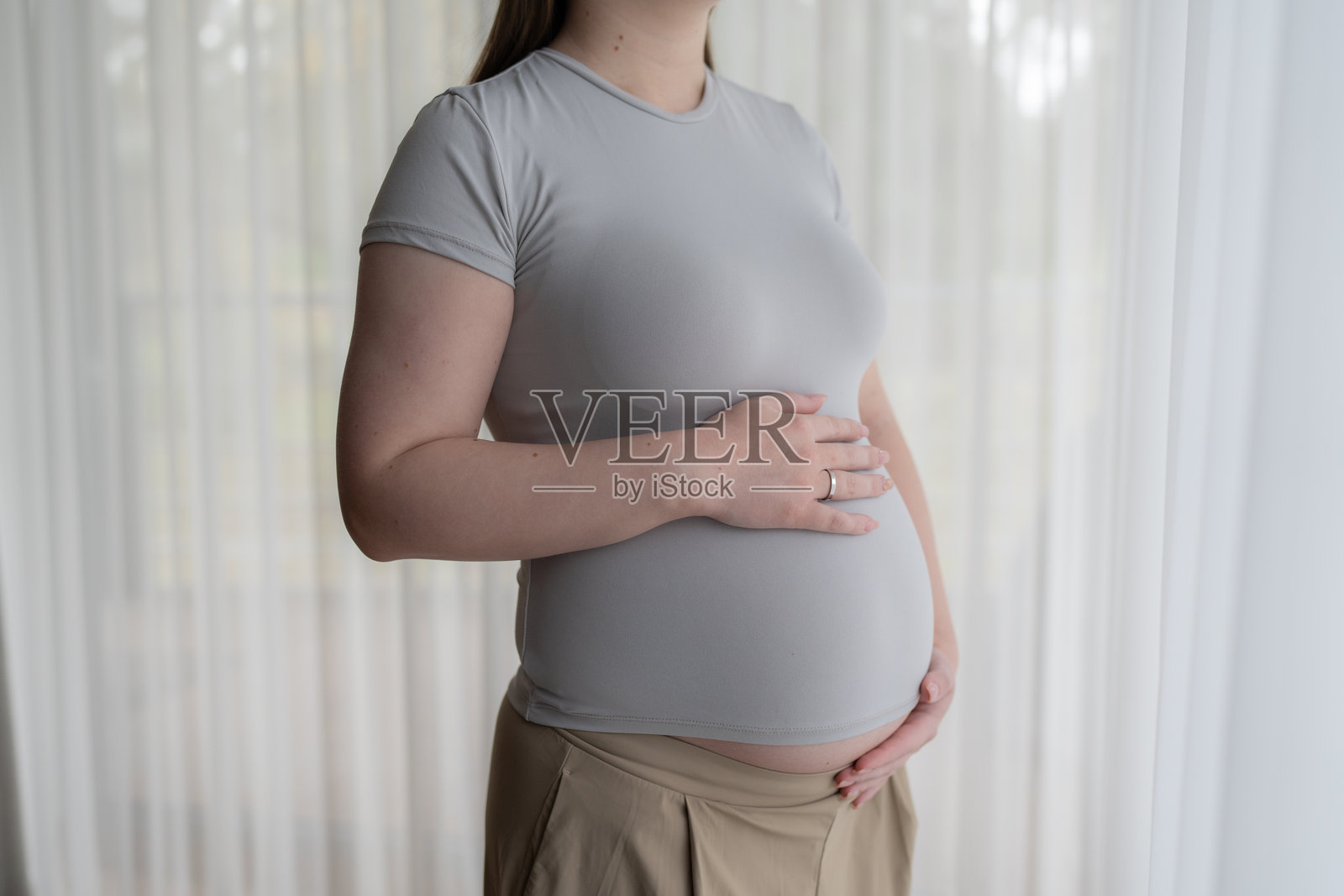 年轻孕妇近距离触摸自己的肚子，关心自己的健康。照片摄影图片