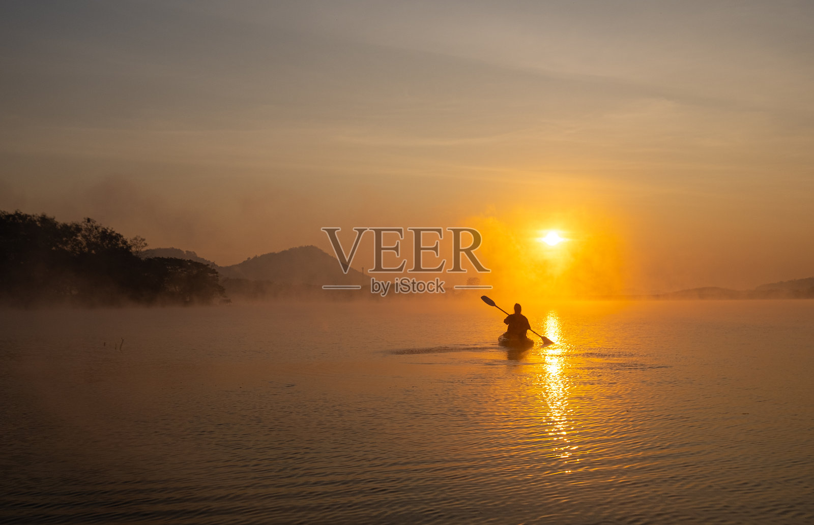 女性在泰国洛伊的怀南曼水库哈里拉克森林公园的水库中划皮划艇，日出时分，2023年1月21日。照片摄影图片