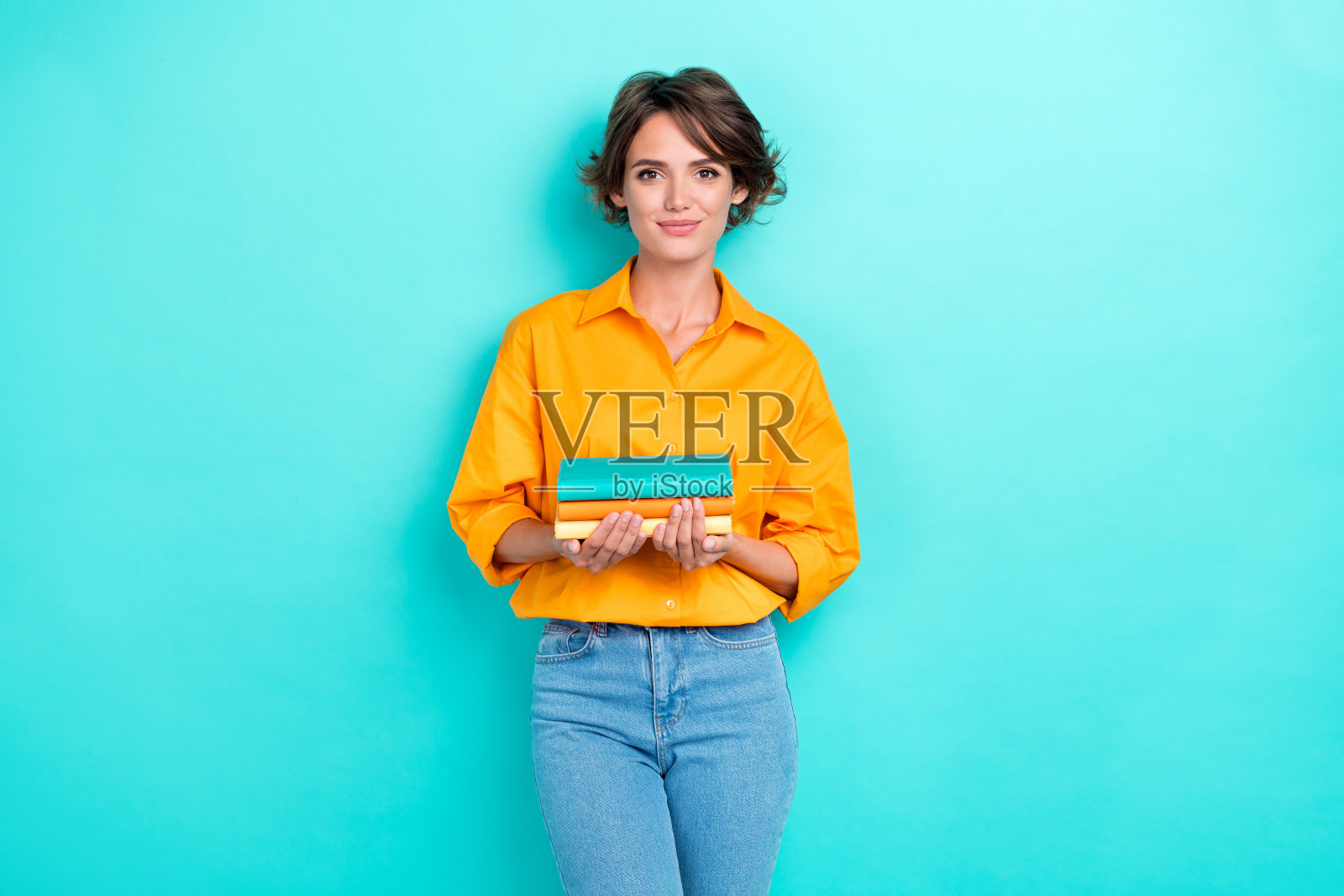 年轻迷人可爱的女性穿着明亮的衬衫，手持日记本，自信积极，背景为青色。照片摄影图片