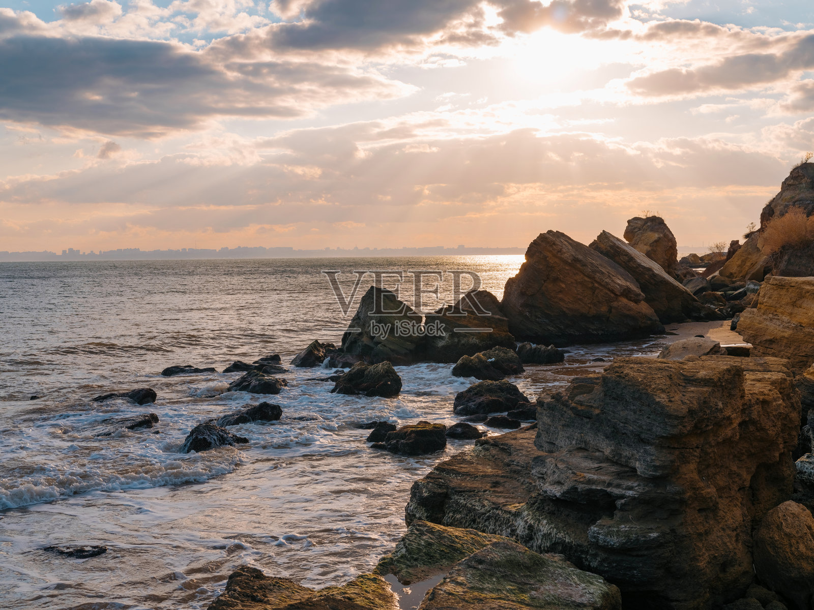 黑海海岸日落时美丽的海景，岩石与阳光透过云层洒下的光芒。照片摄影图片