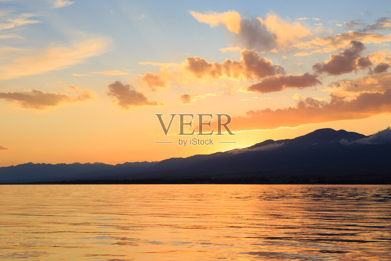 五彩斑斓的海滩与山脉日出，深蓝色的天空和阳光透射。自然背景。照片摄影图片