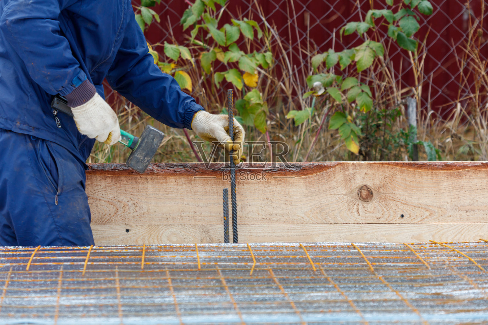 一名穿着蓝色夹克的男子正在进行一个项目，使用锤子和钉枪。照片摄影图片