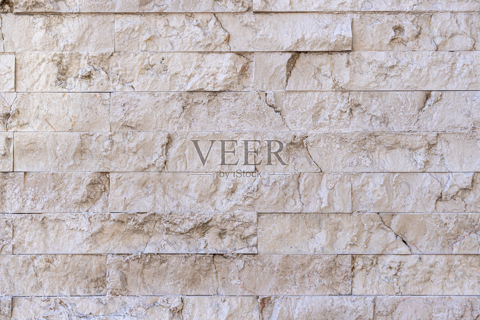 用米色瓷砖错落排列而成的石墙。照片摄影图片