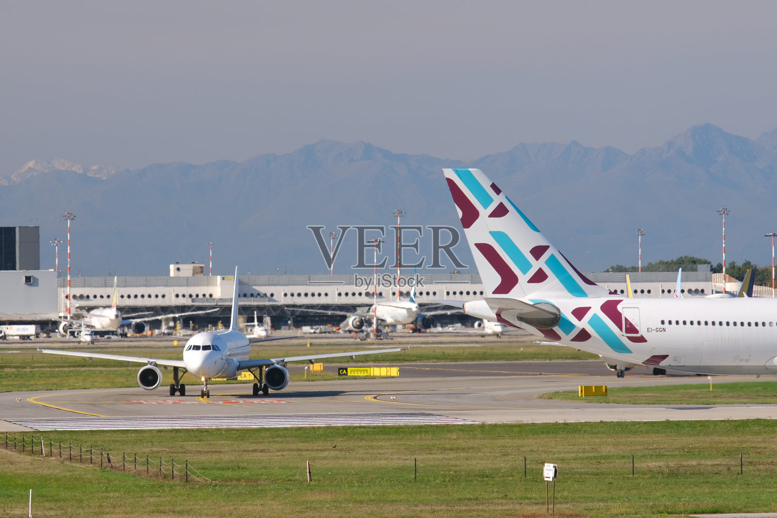 保加利亚航空的空客A320-214飞机停在马尔彭萨机场跑道上。背景是1号航站楼的建筑和停放的飞机。照片摄影图片
