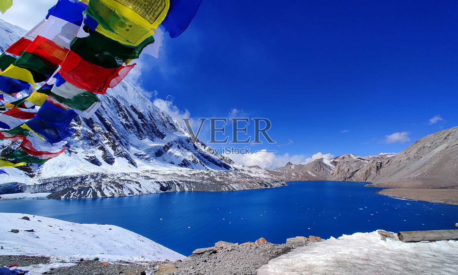令人惊叹的蒂利乔湖被五彩缤纷的祈祷旗环绕，静静地坐落在安娜普尔纳山脉的雪峰之间。照片摄影图片