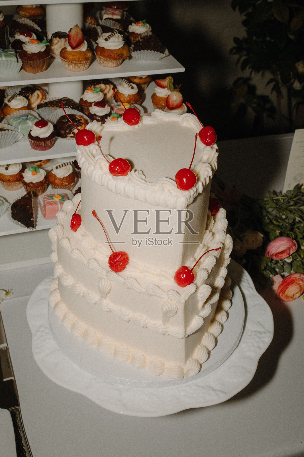 三层婚礼蛋糕，涂有白色黄油霜，并装饰有红樱桃照片摄影图片