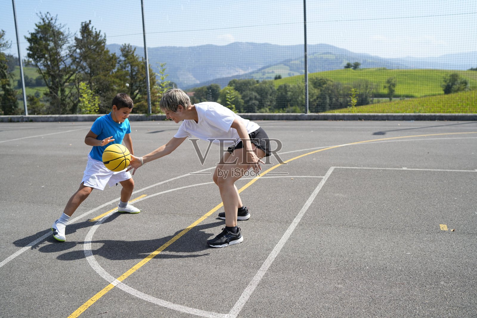 母亲和儿子在户外篮球场上打篮球照片摄影图片