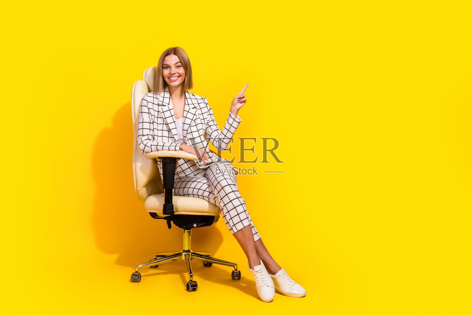 自信的年轻女商人在时尚的格子西装中摆姿势，背景为黄色，表达创意想法。照片摄影图片