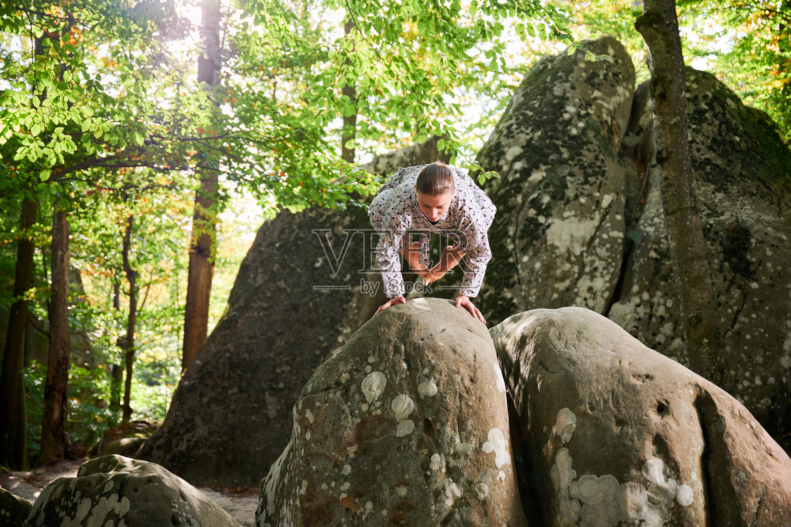 女性在森林中户外练习瑜伽。赤脚的女性在瑜伽垫上，周围是树木和岩石。照片摄影图片