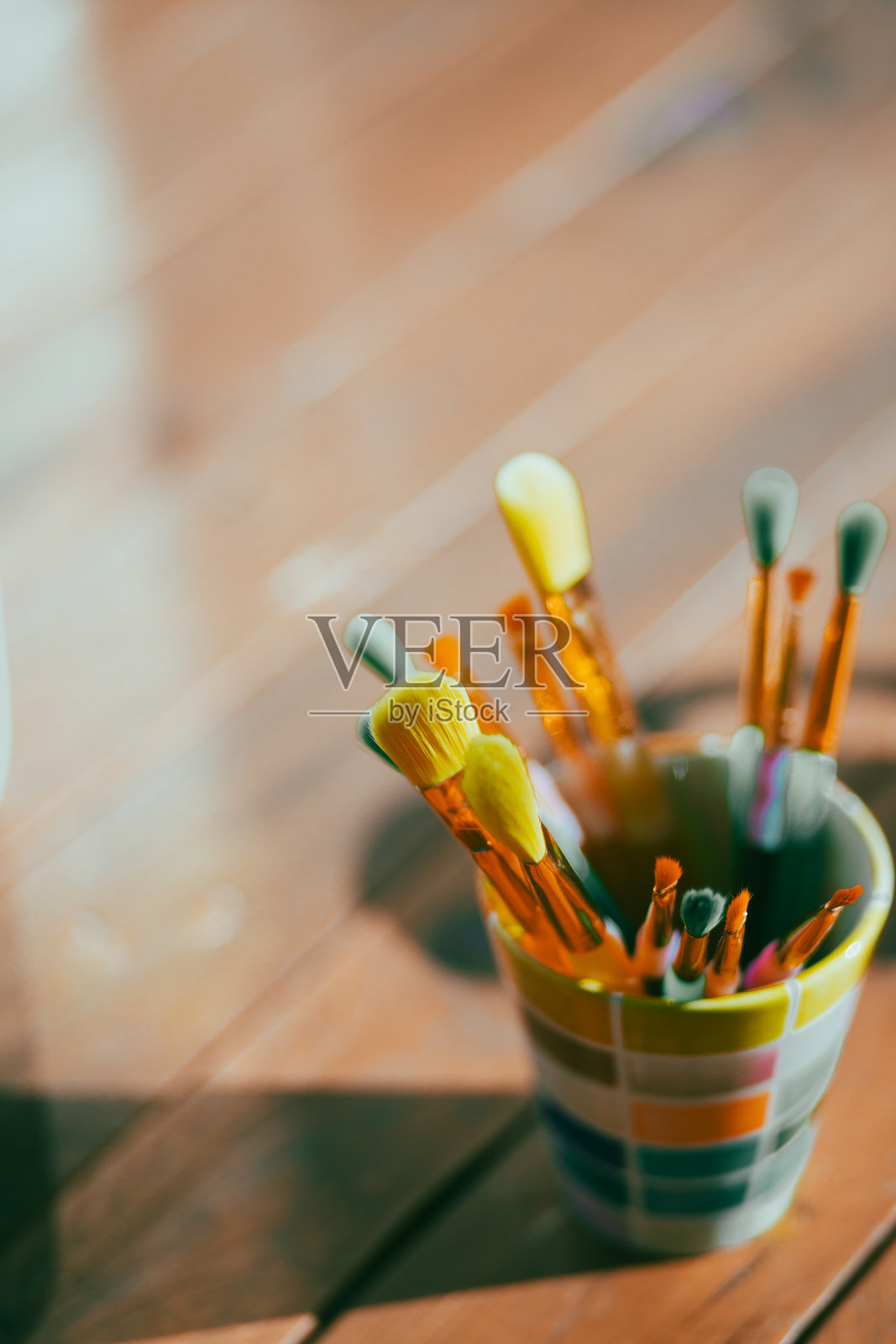 许多彩色画笔放在一个彩色的罐子里，摆放在木桌上照片摄影图片