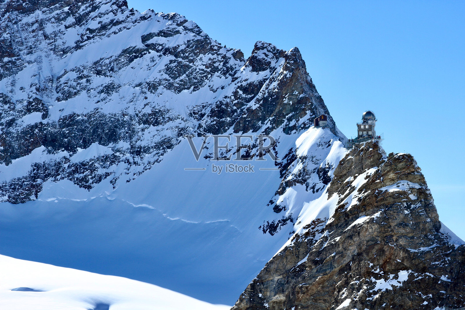 少女峰的斯芬克斯天文台坐落在瑞士伯尔尼阿尔卑斯山的少女峰鞍部，背景是蓝天。照片摄影图片