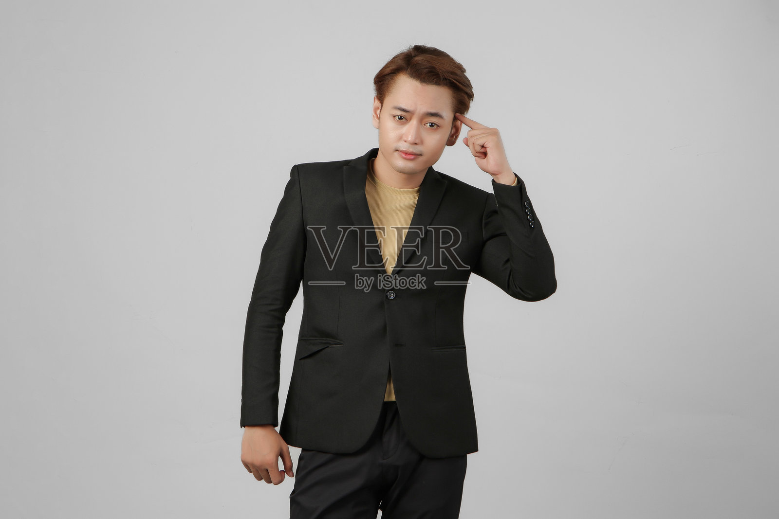 身穿西装的沉思亚洲商人肖像，做出思考手势，背景为纯色。照片摄影图片