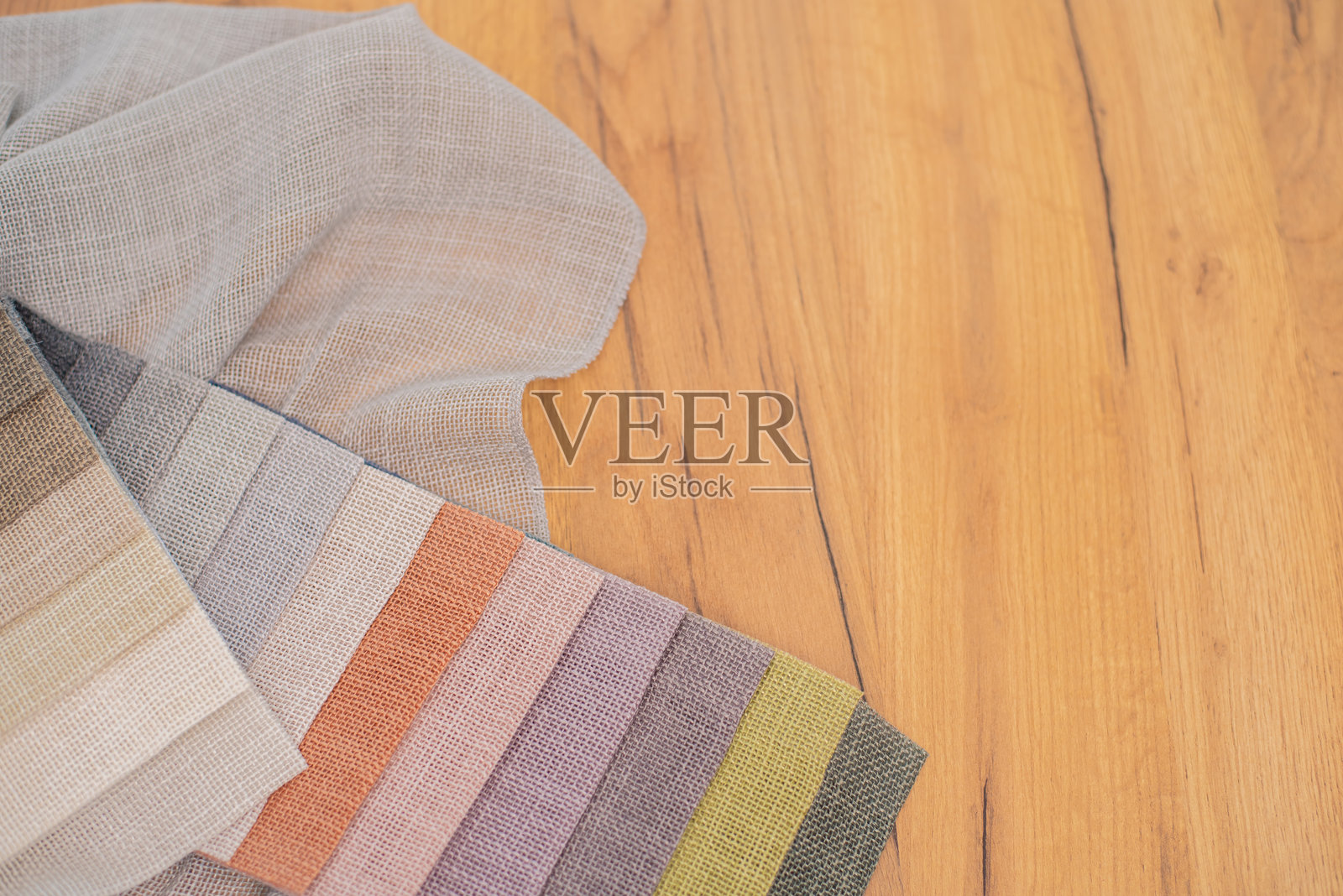 木质背景上的亚麻色窗帘面料。米色、粉色和橙色的亚麻面料。照片摄影图片