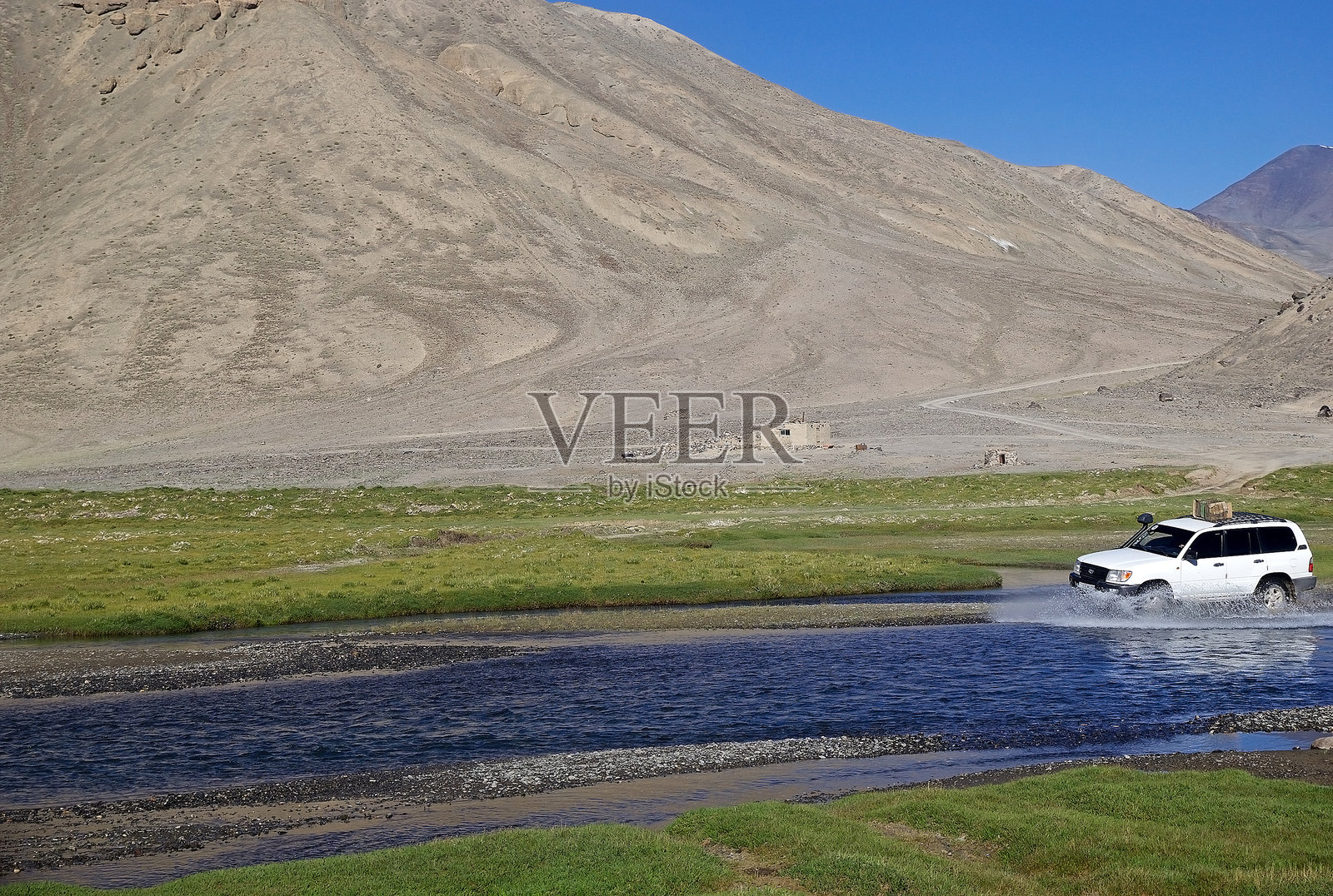 越野车正在塔吉克斯坦戈尔诺-巴达赫尚地区的巴尔唐谷沿河涉水。照片摄影图片