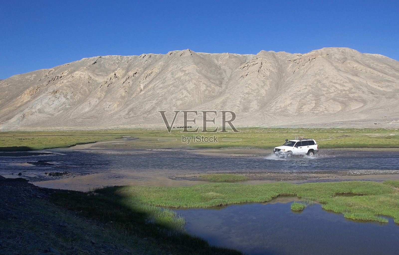越野车正在塔吉克斯坦戈尔诺-巴达赫尚地区的巴尔唐谷沿河涉水。照片摄影图片