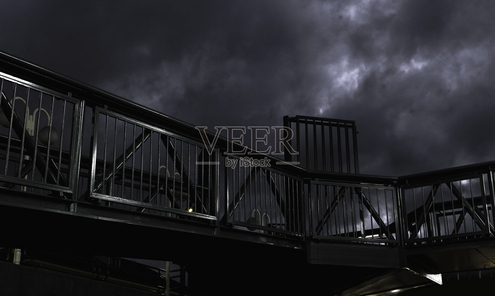 一座有栏杆的桥和阴暗的天空。天空被乌云笼罩，显得阴沉。照片摄影图片