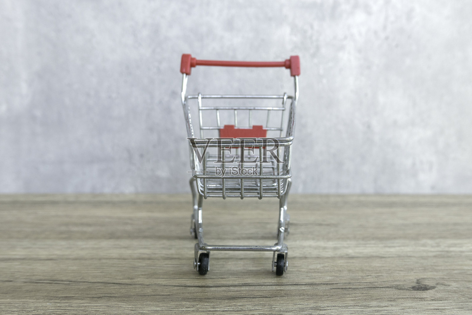 木质表面上的迷你购物车，背景为灰色照片摄影图片