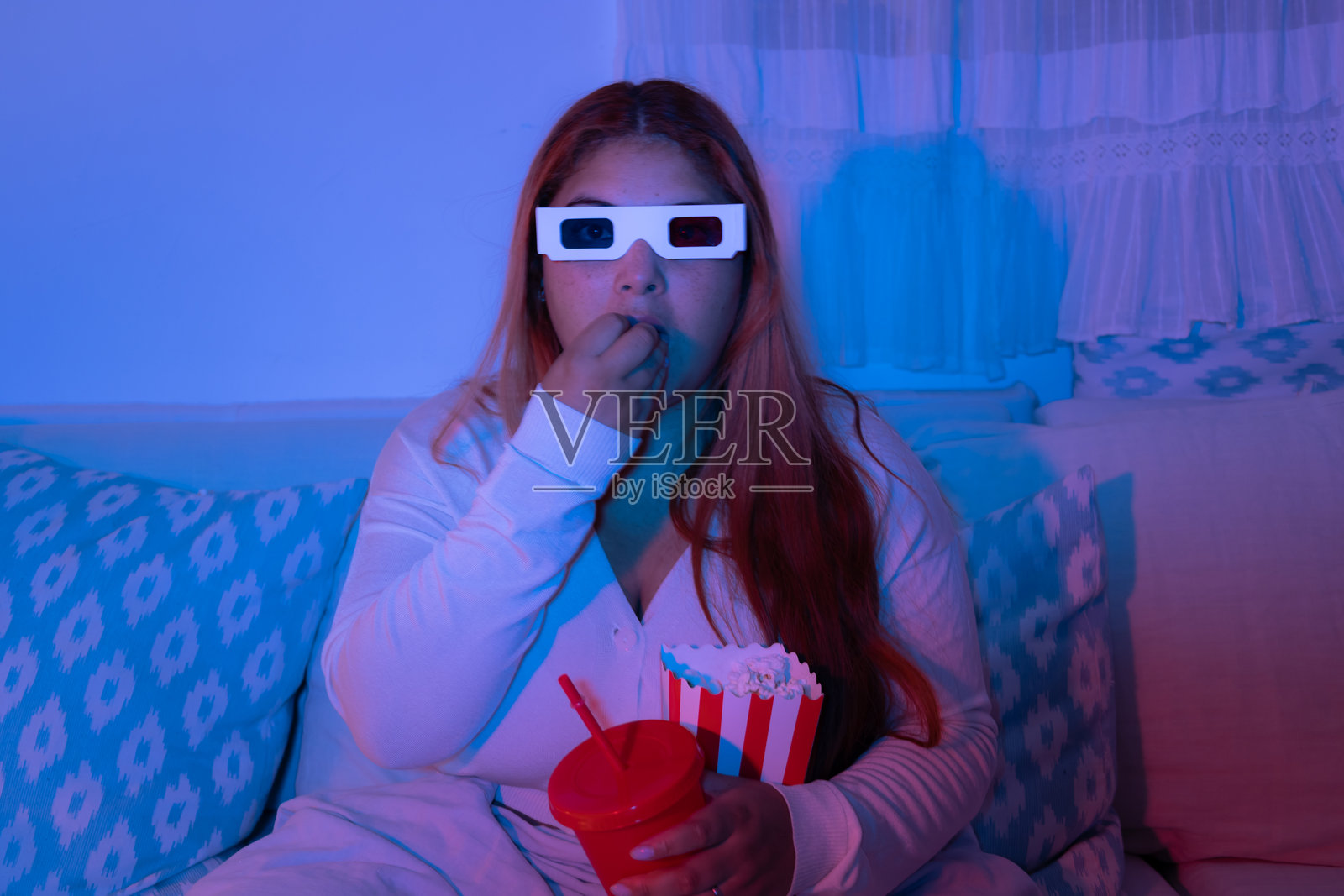 年轻女性在看电影时吃爆米花照片摄影图片