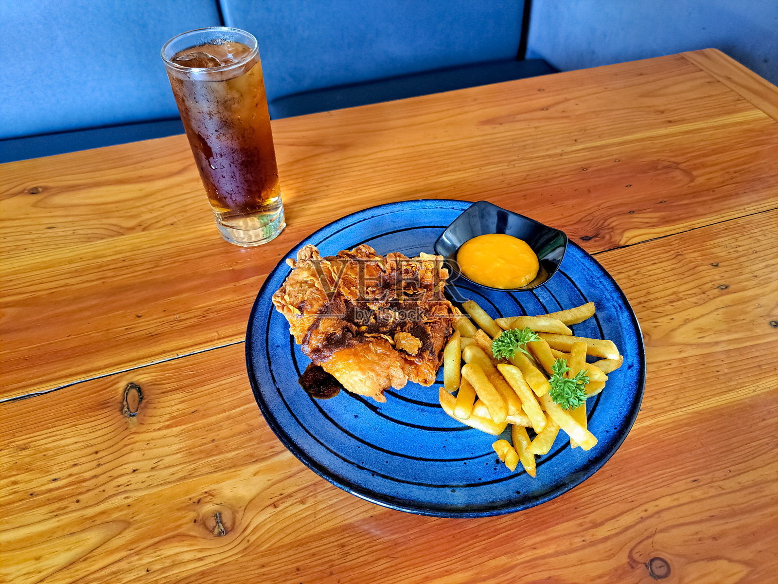 纳什维尔热鸡配薯条和奶酪酱，摆放在盘子上。新鲜冰茶装在玻璃杯中。食品和饮料菜单。照片摄影图片