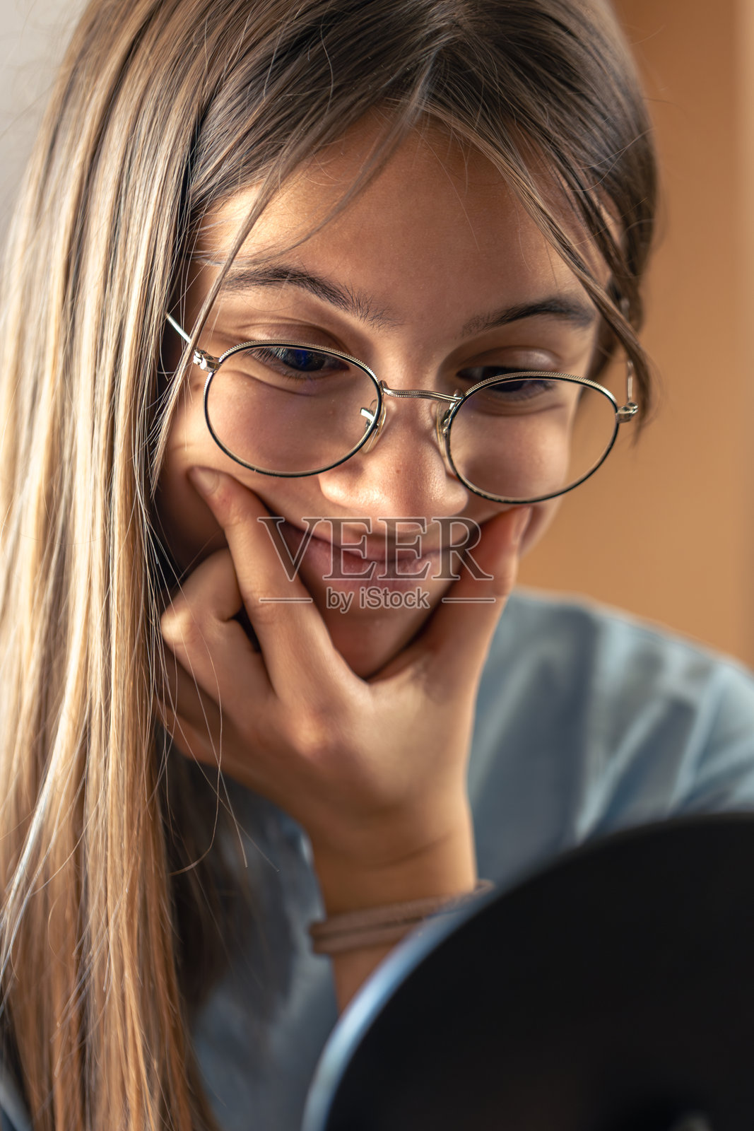 一个戴眼镜的美丽女孩在镜子前看着自己。早晨日常。照片摄影图片