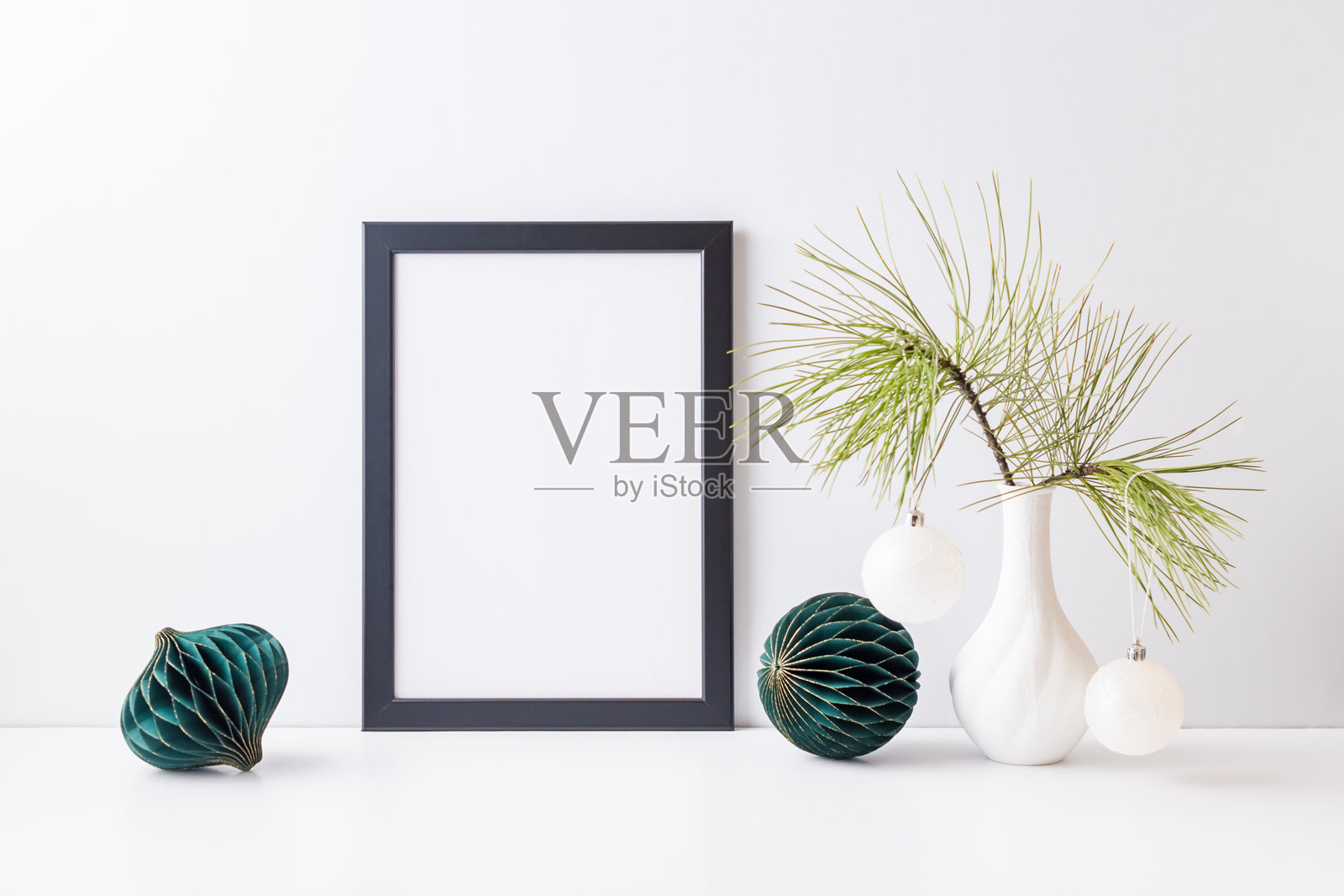 黑色海报框的样板，配有家居室内的圣诞装饰，斯堪的纳维亚风格。白色桌子上有圣诞小屋、鹿和花瓶里的树枝。照片摄影图片