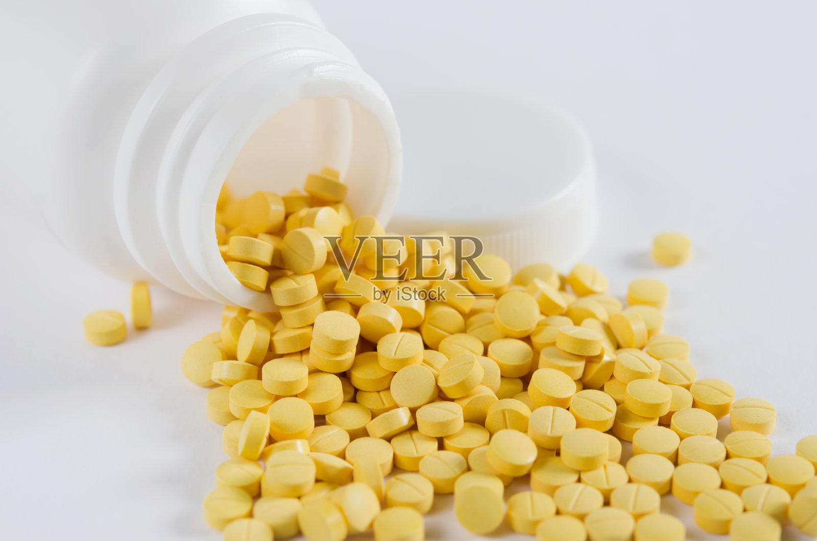 从容器中倾倒的黄色药丸在灰色背景上的俯视图照片摄影图片