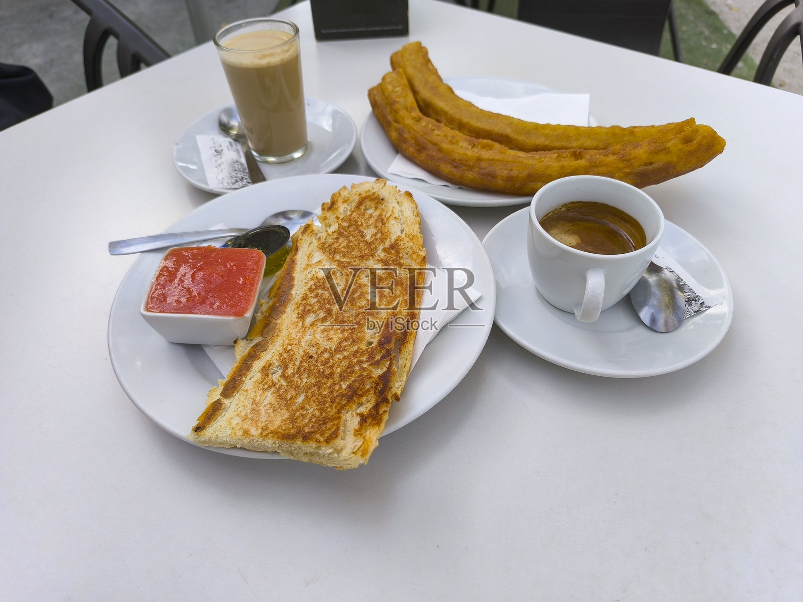 马德里典型的早餐：咖啡、油条和涂抹天然番茄的烤面包。照片摄影图片